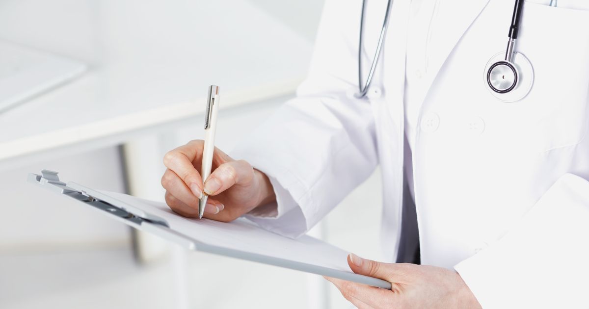doctor in white coat writing on clipboard for patient injured at work